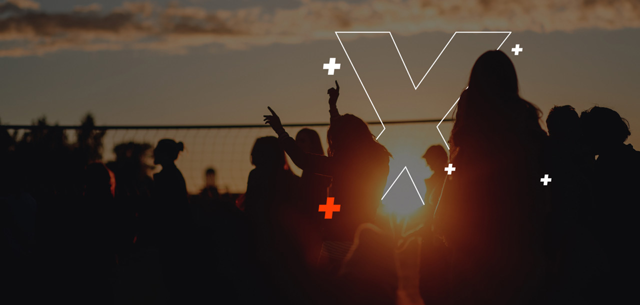 A group of people dancing and socializing at sunset.